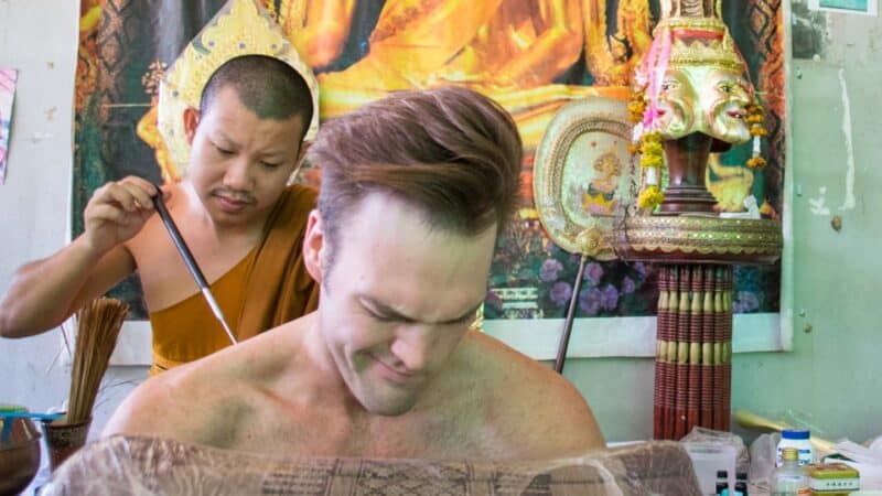 Adam haciéndose un tatuaje Sak Yant cara de dolor