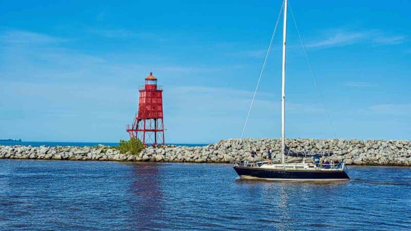 sail boat in the water going by the Racine Breakwater Lighthouse