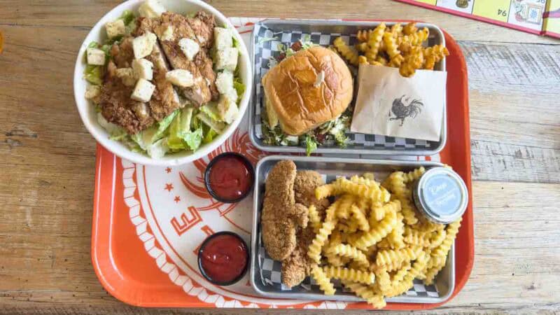 Coop De Ville restaurant tray with a chicken salad, sandwich, chicken tenders, and fries